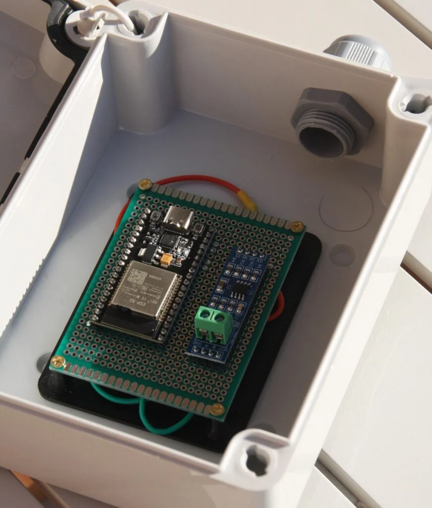 Una placa electrónica sujeta a un soporte impreso en 3D, montada dentro de una caja estanca.
