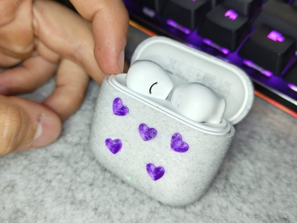 Funda blanca moteada para una caja de auriculares, con corazones morados pintados a mano.