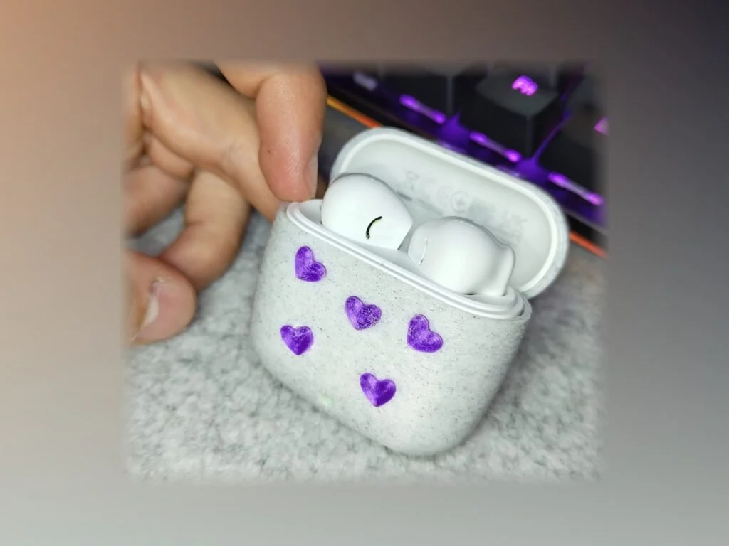 Funda blanca moteada para una caja de auriculares, con corazones morados pintados a mano.